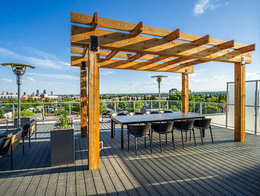 A wooden pergola with a table and chairs on a deck.