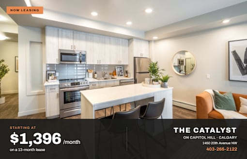 A modern kitchen with a white island and stainless steel appliances is on lease for $1,396 per month.