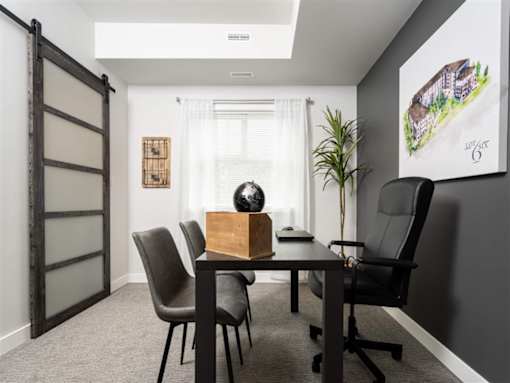 A room with a table and chairs and a painting on the wall.