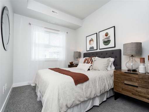 A bedroom with a large bed and a wooden nightstand.
