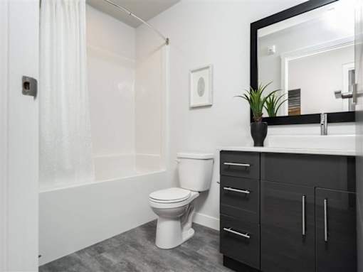 A white toilet sits in a bathroom next to a white bathtub.