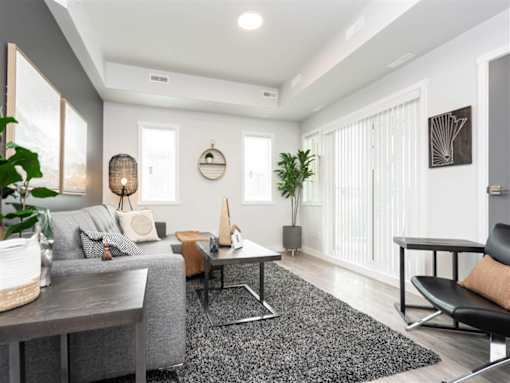 A modern living room with a grey sofa, a black chair, and a wooden coffee table.