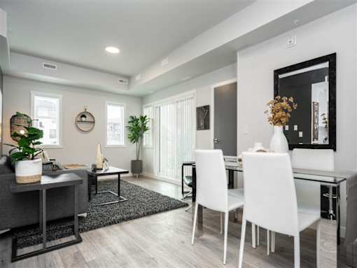 A modern dining room with a glass table and white chairs.