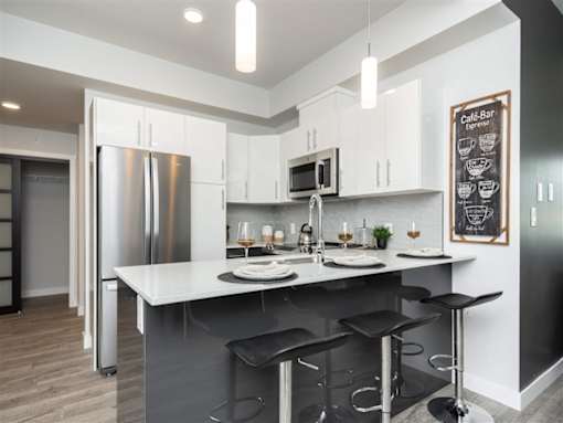 A modern kitchen with a bar stool and a fridge.