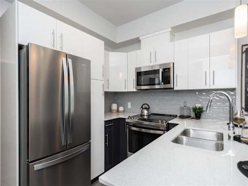 A modern kitchen with a stainless steel refrigerator and black cabinets.