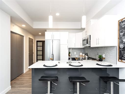 A modern kitchen with a bar area and a chalkboard on the wall.