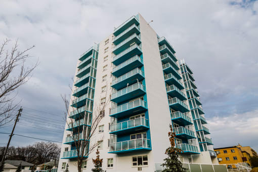 a tall building with green balconies and a cloudy sky