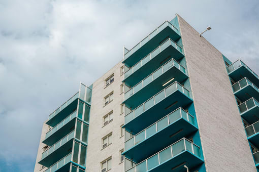 a tall building with balconies and a cloudy sky