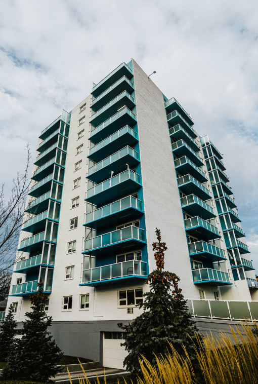 a tall building with green windows and a cloudy sky