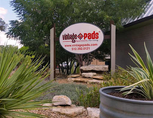 A sign for Vintage Pads Apartments is displayed in front of a building.