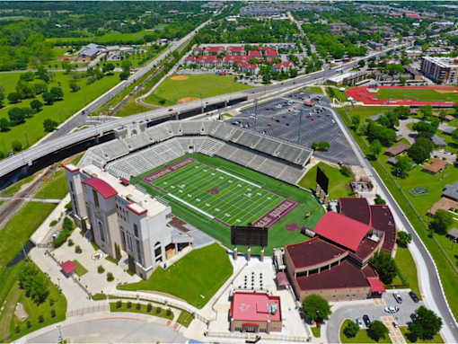 An aerial view of a football stadium with a green field and red seats.