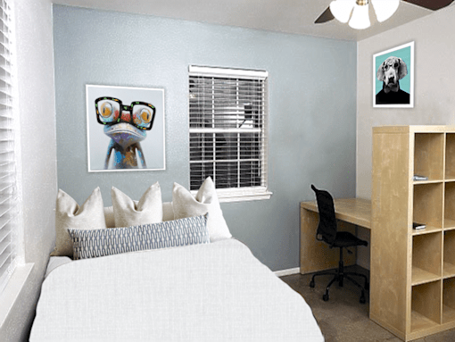 A bedroom with a bed, desk, and a picture of a dog on the wall.