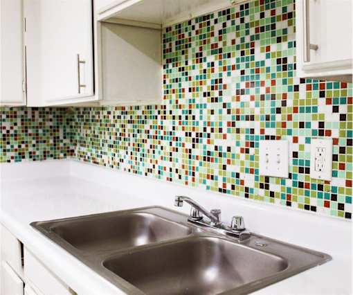 A kitchen with a white sink and a tiled wall.