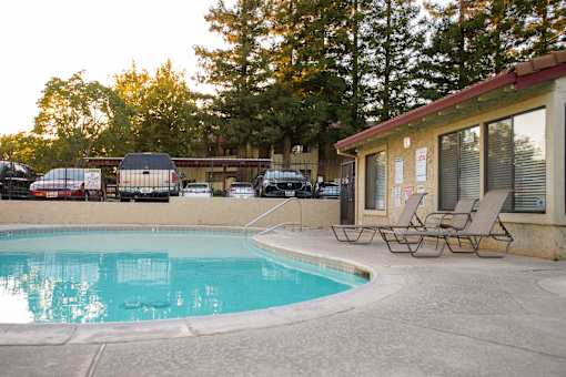 A pool with chairs and a building in the background.