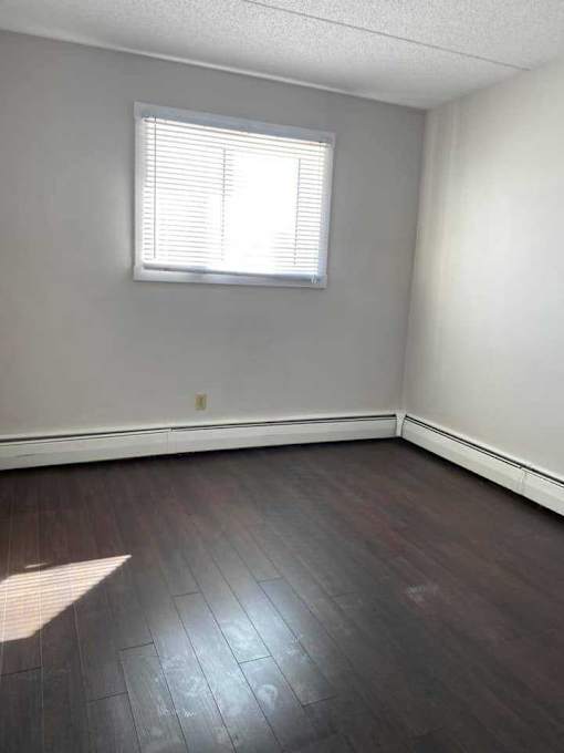 A room with a window and wooden flooring.