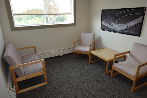 A room with a grey carpet and a painting on the wall.