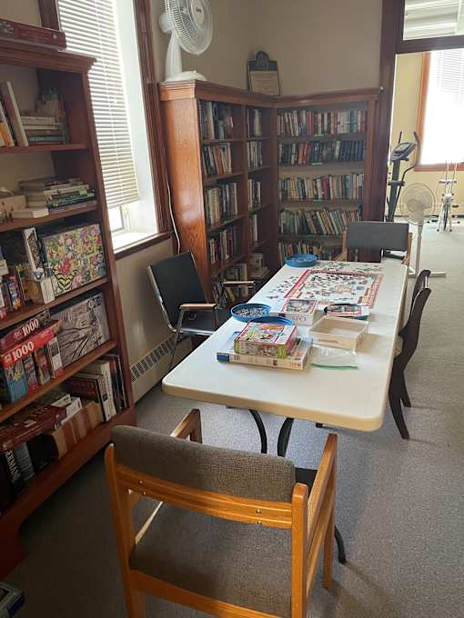 A room with a table, chairs, and a bookshelf filled with books.