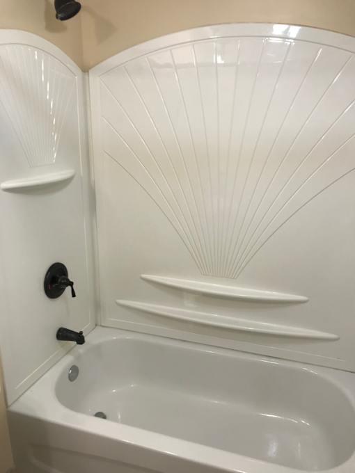 a white bathtub with white walls and black fixtures