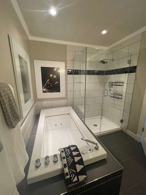 A bathroom with a white tub and a black and white towel.