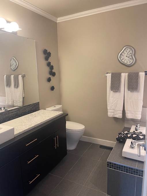 A bathroom with a toilet, sink, and mirror.