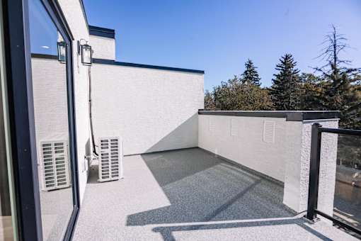A balcony with a white wall and a black railing.