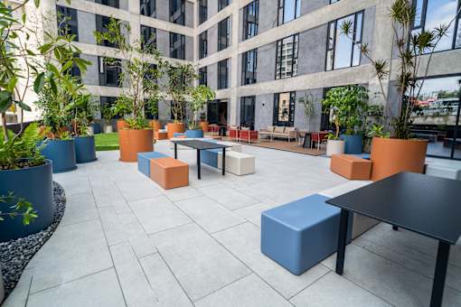 A courtyard with tables and chairs and potted plants.