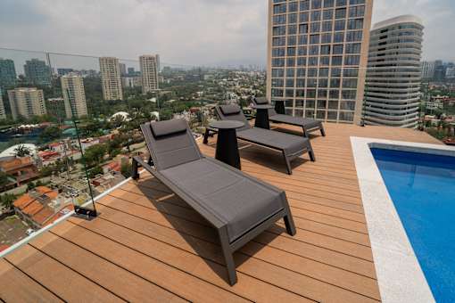 Two sun loungers on a wooden deck overlooking a cityscape.