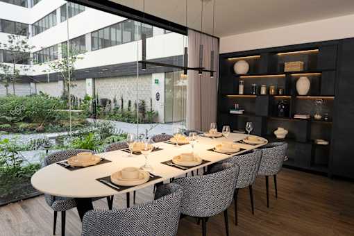 A modern dining room with a long table set for a meal.