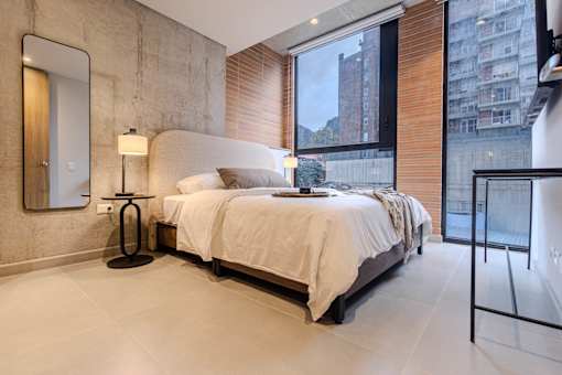 A bedroom with a large bed, a lamp, and a mirror on the wall.