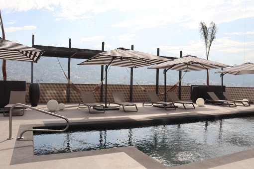 a pool with chairs and umbrellas on top of a roof