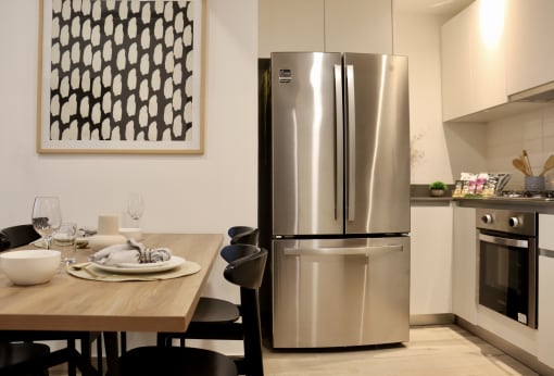 a kitchen with a stainless steel refrigerator and a wooden table