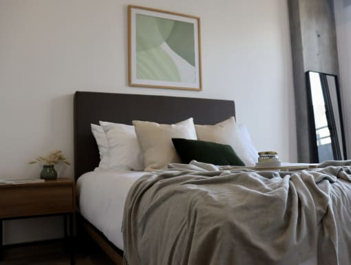 a bedroom with a bed with white pillows and a gray comforter