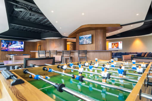 a game room with foosball tables and televisions