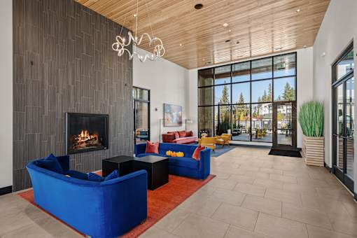 A modern living room with a fireplace and a view of the trees outside.