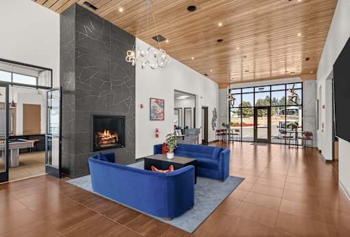 A modern living room with a fireplace and blue couches.