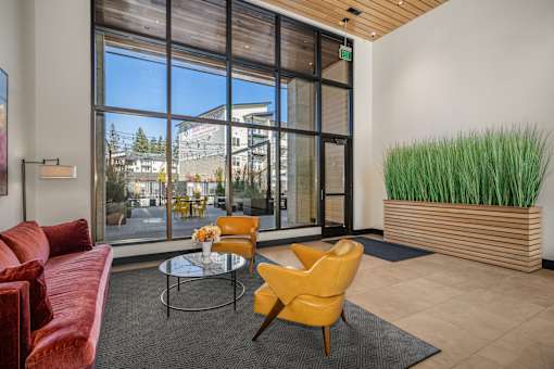 A living room with a red couch, yellow chair, and a glass table.