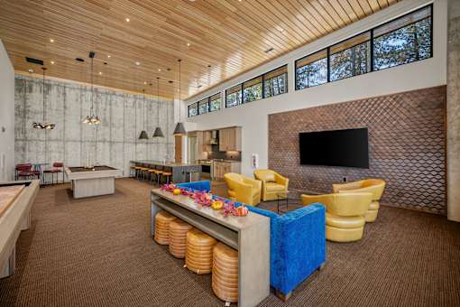 A room with a blue and yellow couch, a pool table, and a television.