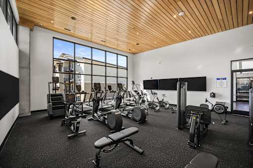 A gym with a variety of equipment including treadmills, weights, and exercise bikes.