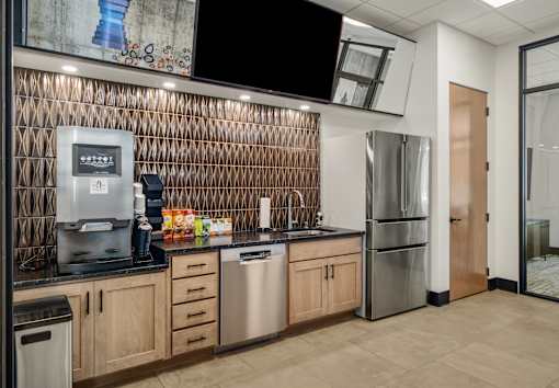 A kitchen with a stainless steel refrigerator, dishwasher, and coffee maker.