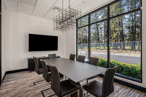 A conference room with a large table and chairs and a flat screen TV mounted on the wall.
