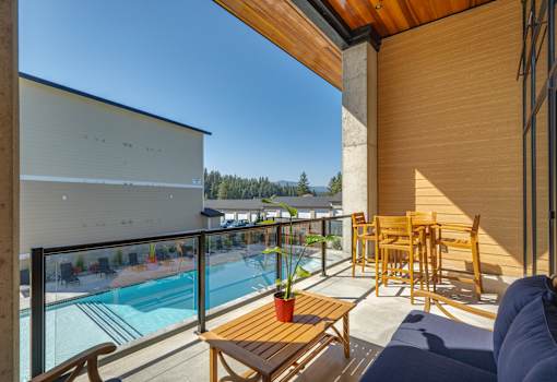 A balcony with a table and chairs overlooking a pool.