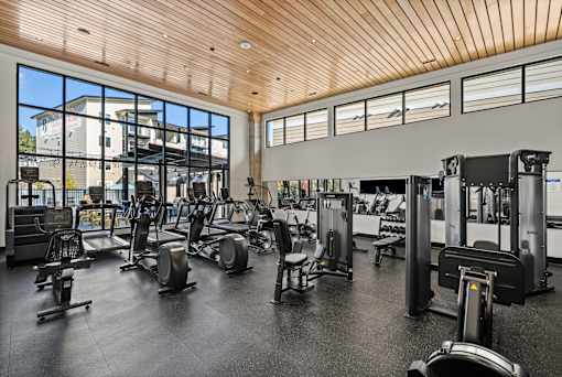A gym with a variety of equipment including treadmills, weights, and exercise machines.
