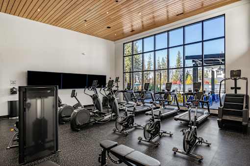 A gym with a variety of exercise equipment including treadmills, stationary bikes, and weight machines.