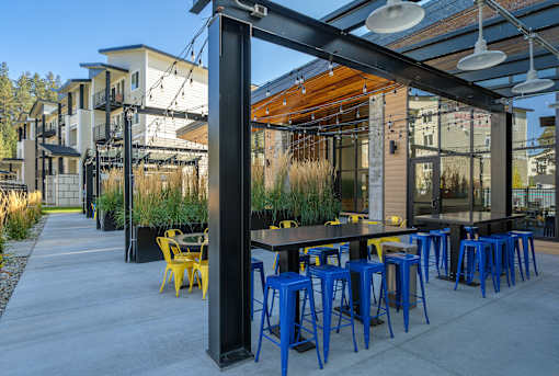 A patio with blue stools and yellow chairs.