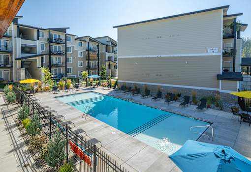 A large swimming pool surrounded by a black fence and a building in the background.