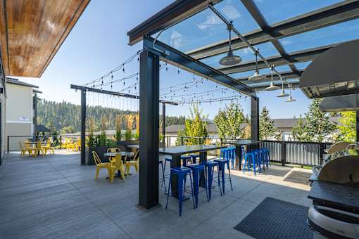 A patio with tables and chairs under a roof with lights.