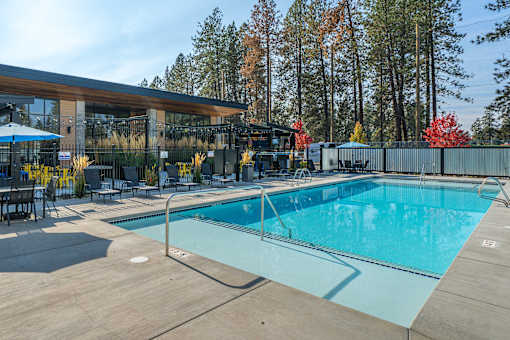 A large outdoor swimming pool with a wooden deck and a building in the background.