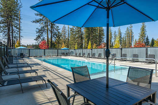 A blue umbrella is on a table next to a pool.