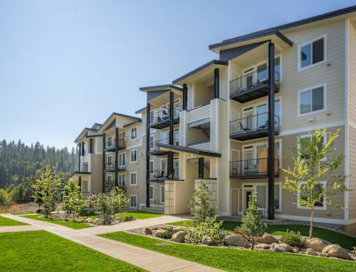 A row of modern apartment buildings with balconies and trees in the foreground.