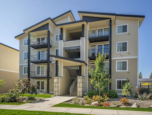 A modern two-story apartment building with balconies and a staircase leading to the entrance.